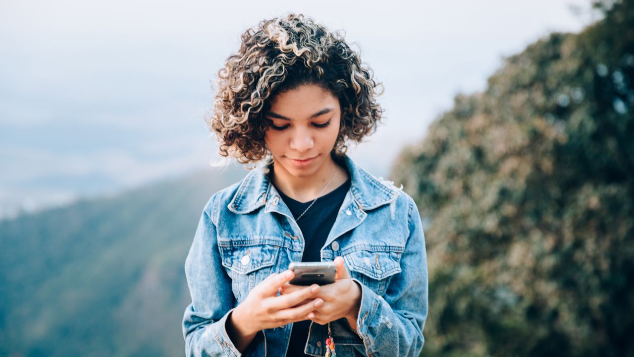 A person standing and looking at a smartphone.