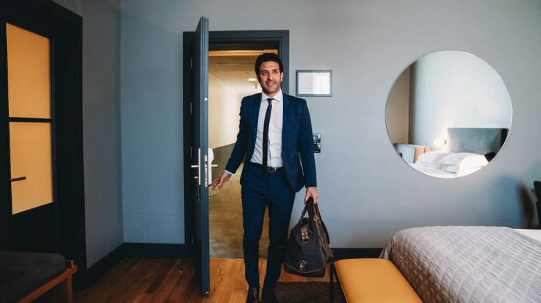 A photo of a person wearing a suit entering a modern hotel room