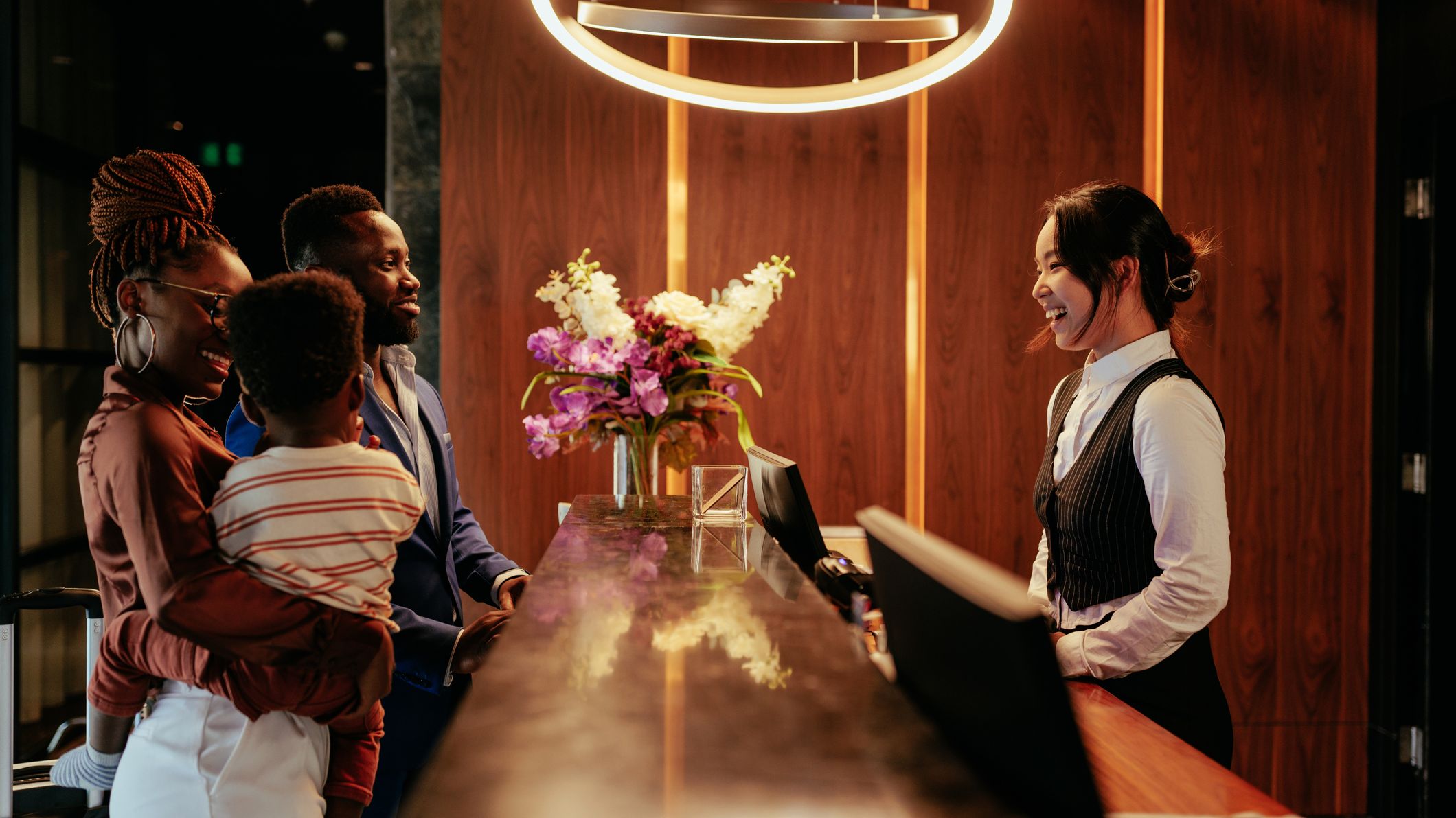 A photo of a family checking into a hotel at the front desk