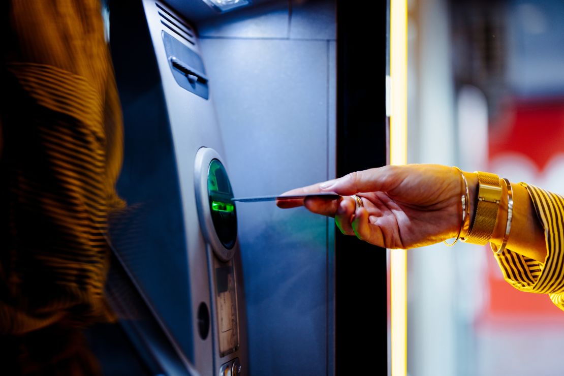 A hand putting a debit card into an ATM