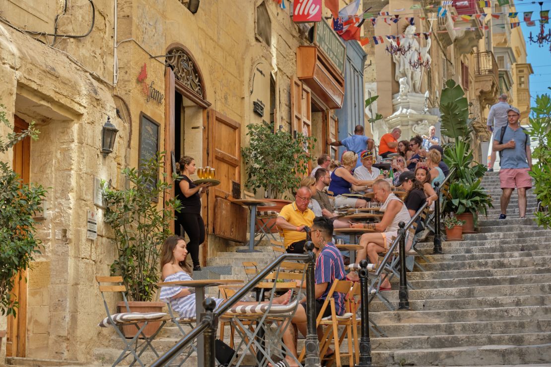 A photo of tourists eating and drinking at a cafe on the steps of St. Lucia street in Valletta, Malta