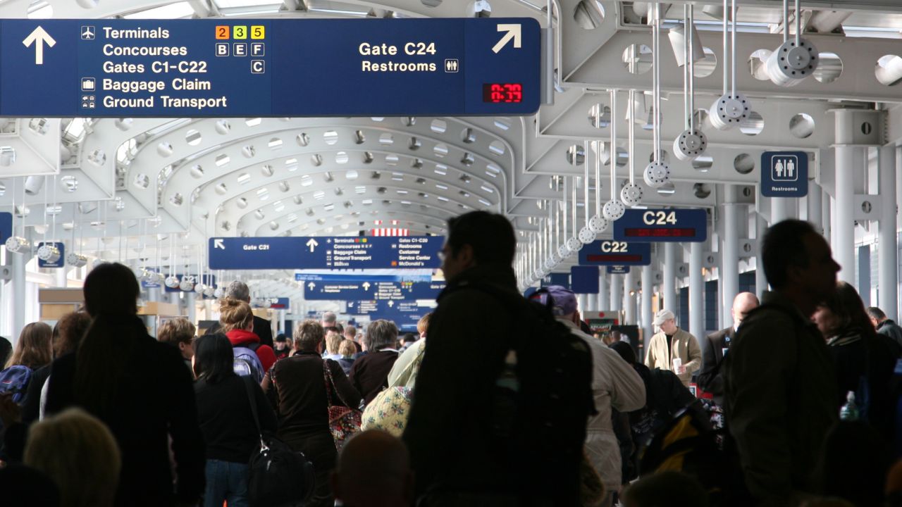 A photo of passengers walking through a crowded airport concourse in Chicago O'Hare International Airport.