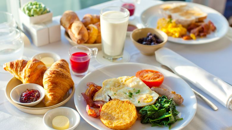 A photo of a large hotel breakfast for two people with eggs, pastries and other breakfast food items on a table