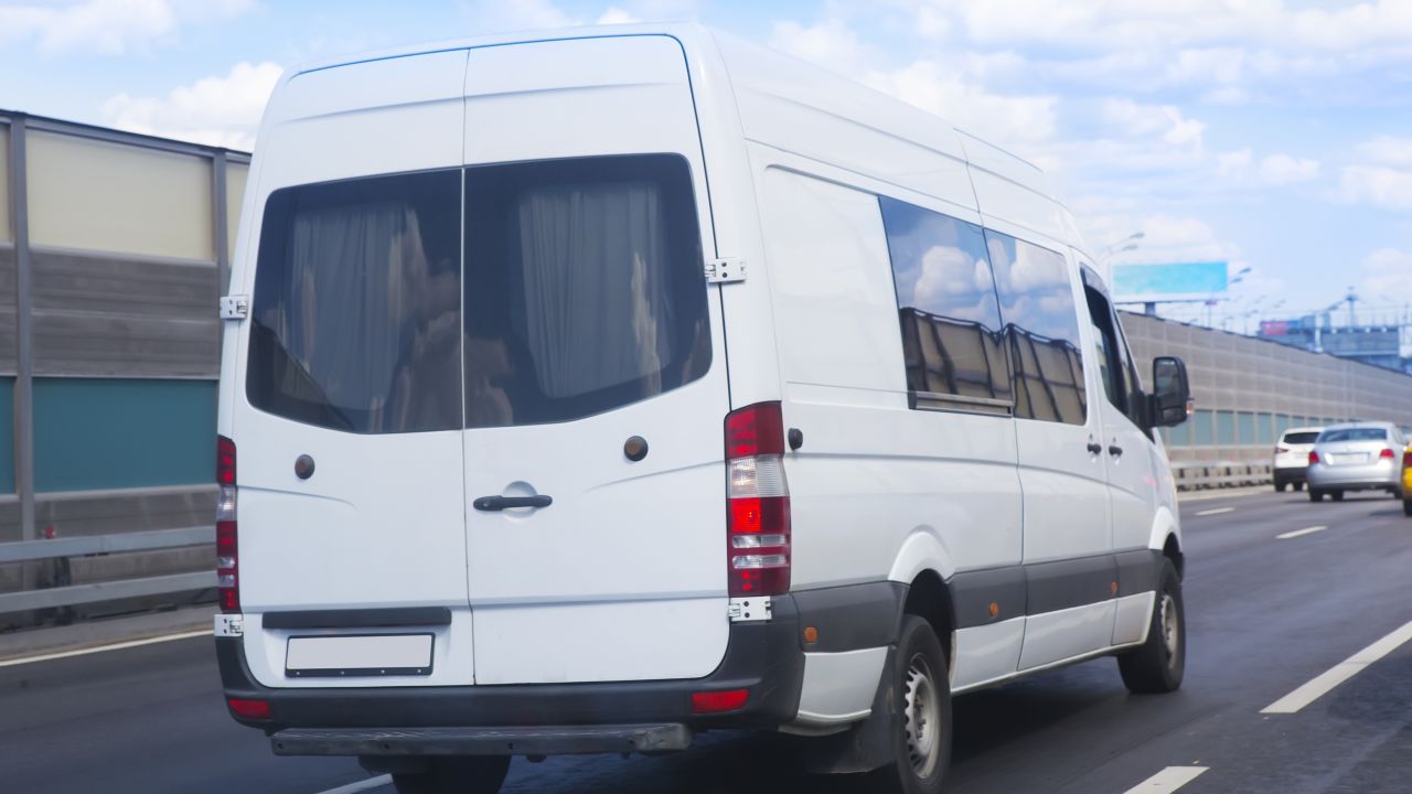 A photo of a white passenger van driving down a highway