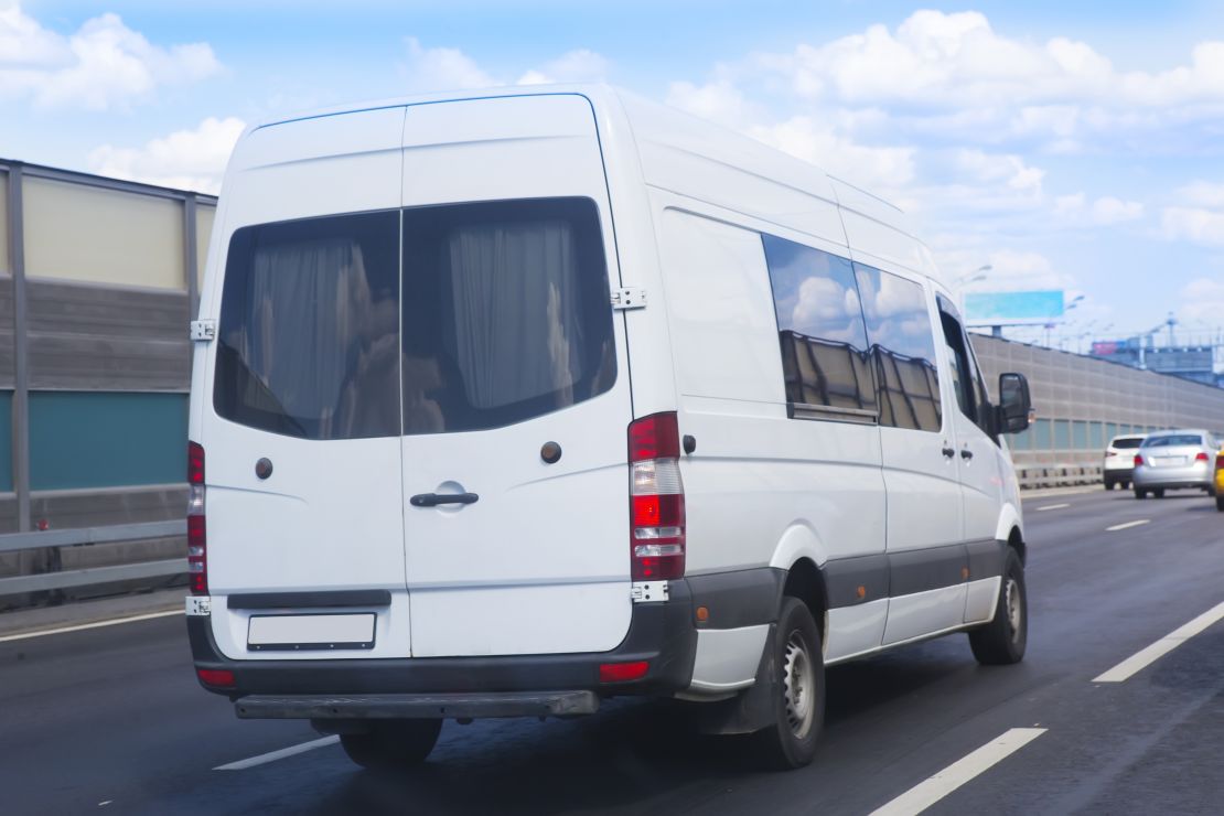 A photo of a white passenger van driving down a highway 