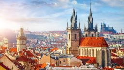 High spires towers of the Tyn Church in Prague with red roofs of houses in the Old Town neighborhood.