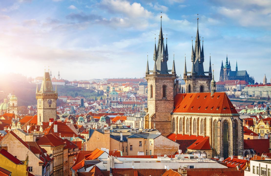 High spires towers of the Tyn Church in Prague with red roofs of houses in the Old Town neighborhood.