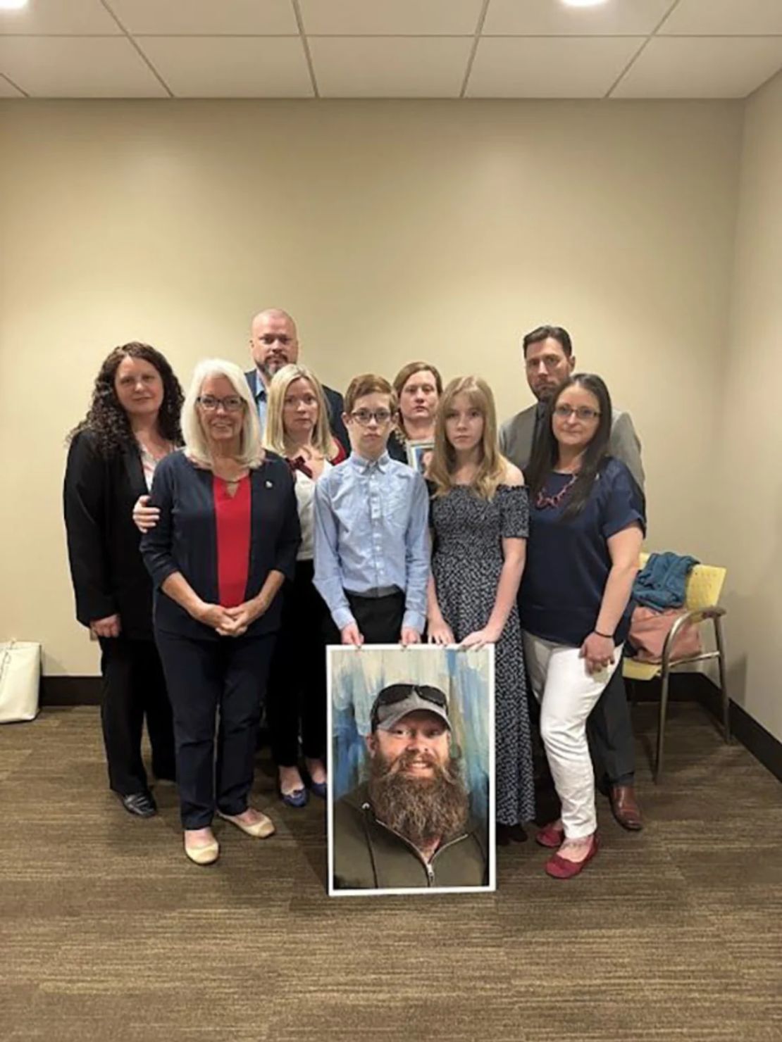 Los familiares de Christopher Pelkey, incluyendo a Stacey Wales (cuarta desde la izquierda), posan con una foto de Pelkey.