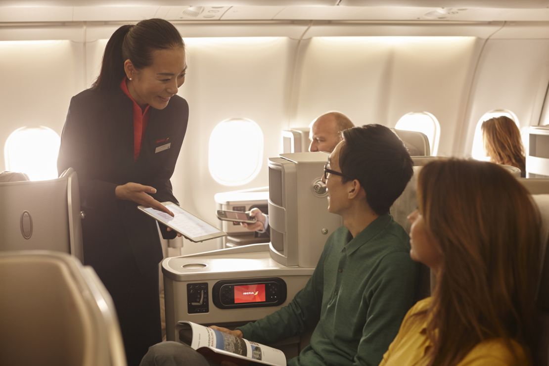 A photo of two people being served by a flight attendant in Iberia business class