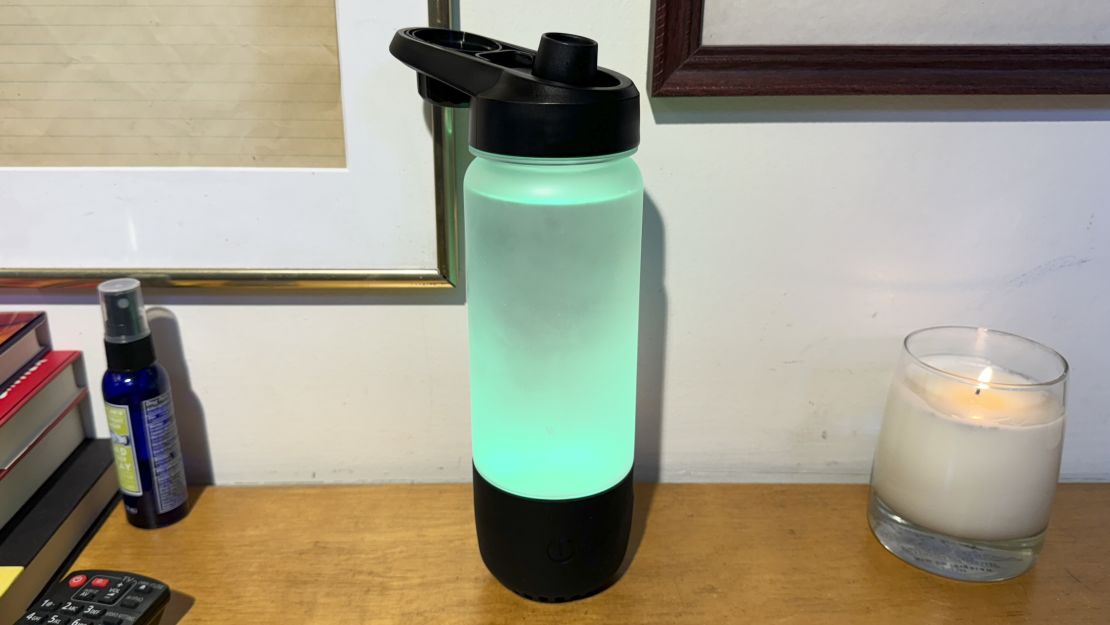 The Icewater 3 in 1 smart water bottle glows green on a counter