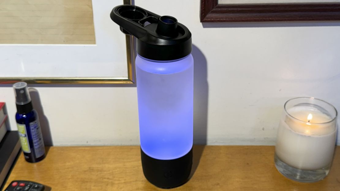 The Icewater 3 in 1 smart water bottle glows blue on a counter