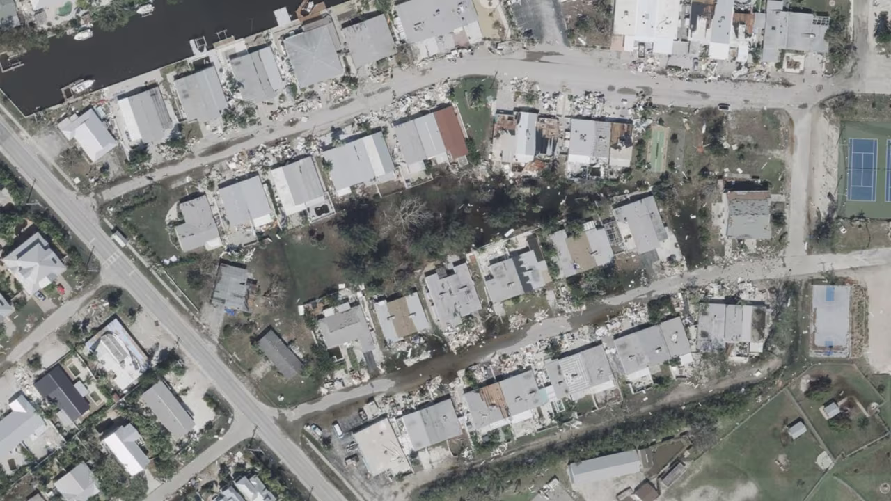 Puddles from Hurricane Milton's storm surge are seen in an area of Holmes Beach on Anna Maria Island, Florida. On the edges of the flooded area sits debris piles from damage caused by Hurricane Helene's own storm surge on the island.