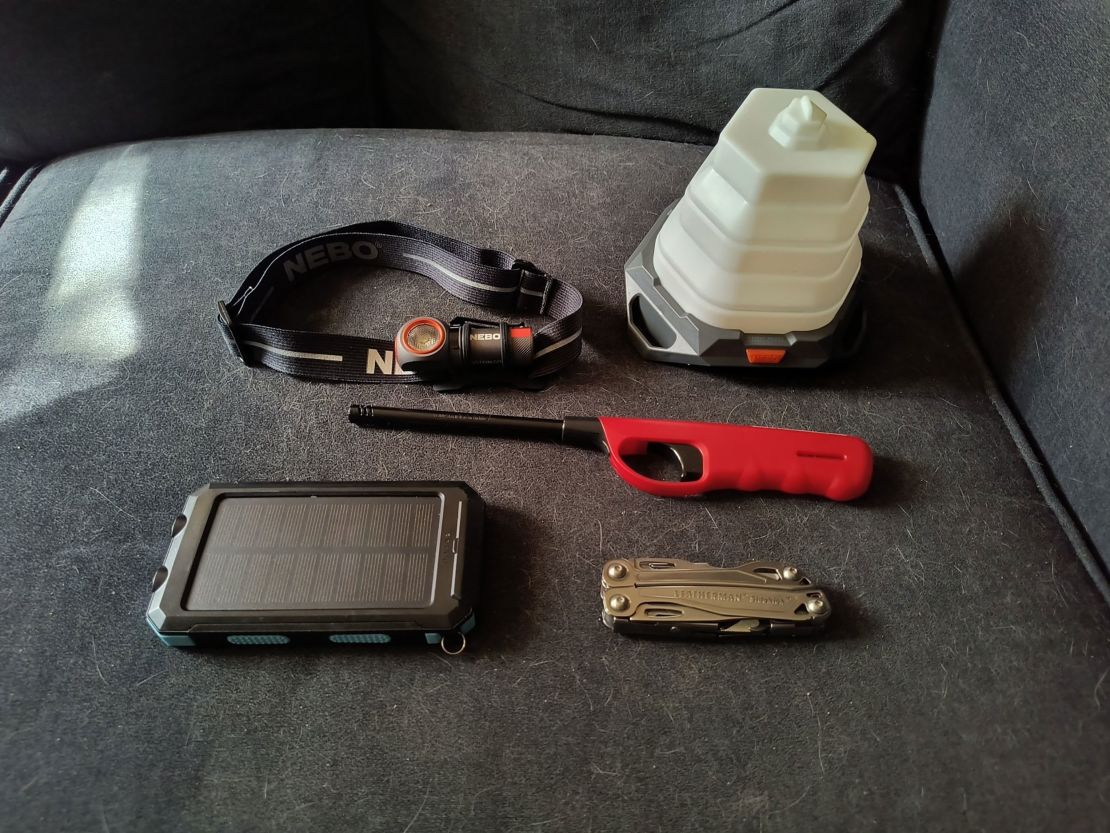 Photo shows Kolosna's supplies: A fold-up lantern, a multitool, a battery bank, a headlight and a stove lighter.