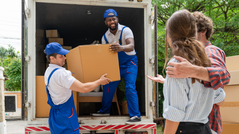 Professional movers unload a truck for a couple.