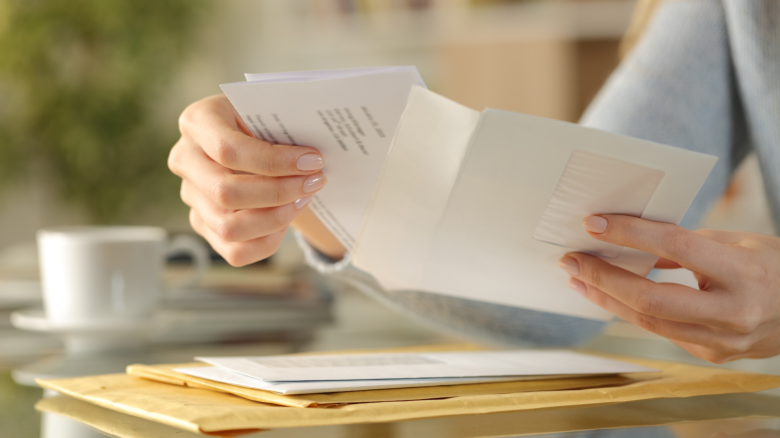 Woman opens envelope on a desk at home