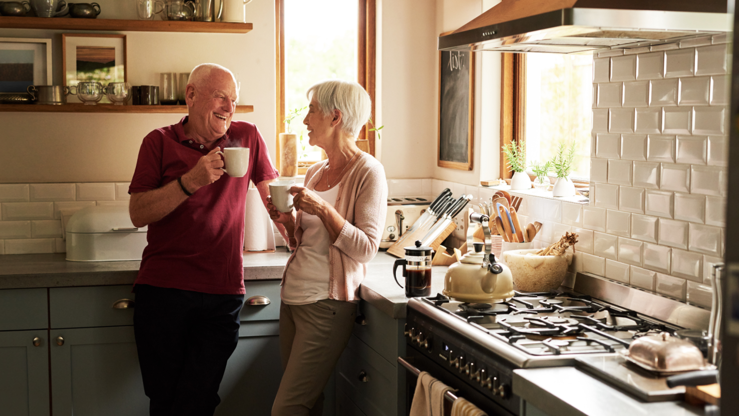 A couple drinks coffee together in a home kitchen.