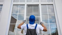 Window installer is replacing a screen on a large window.