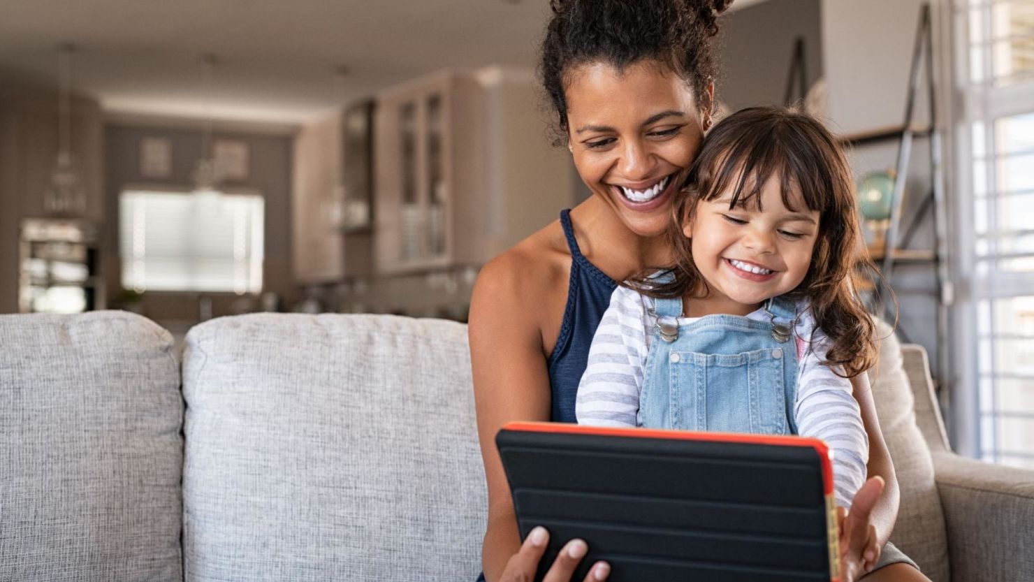 Mother and daughter smiling while using a digital tablet.