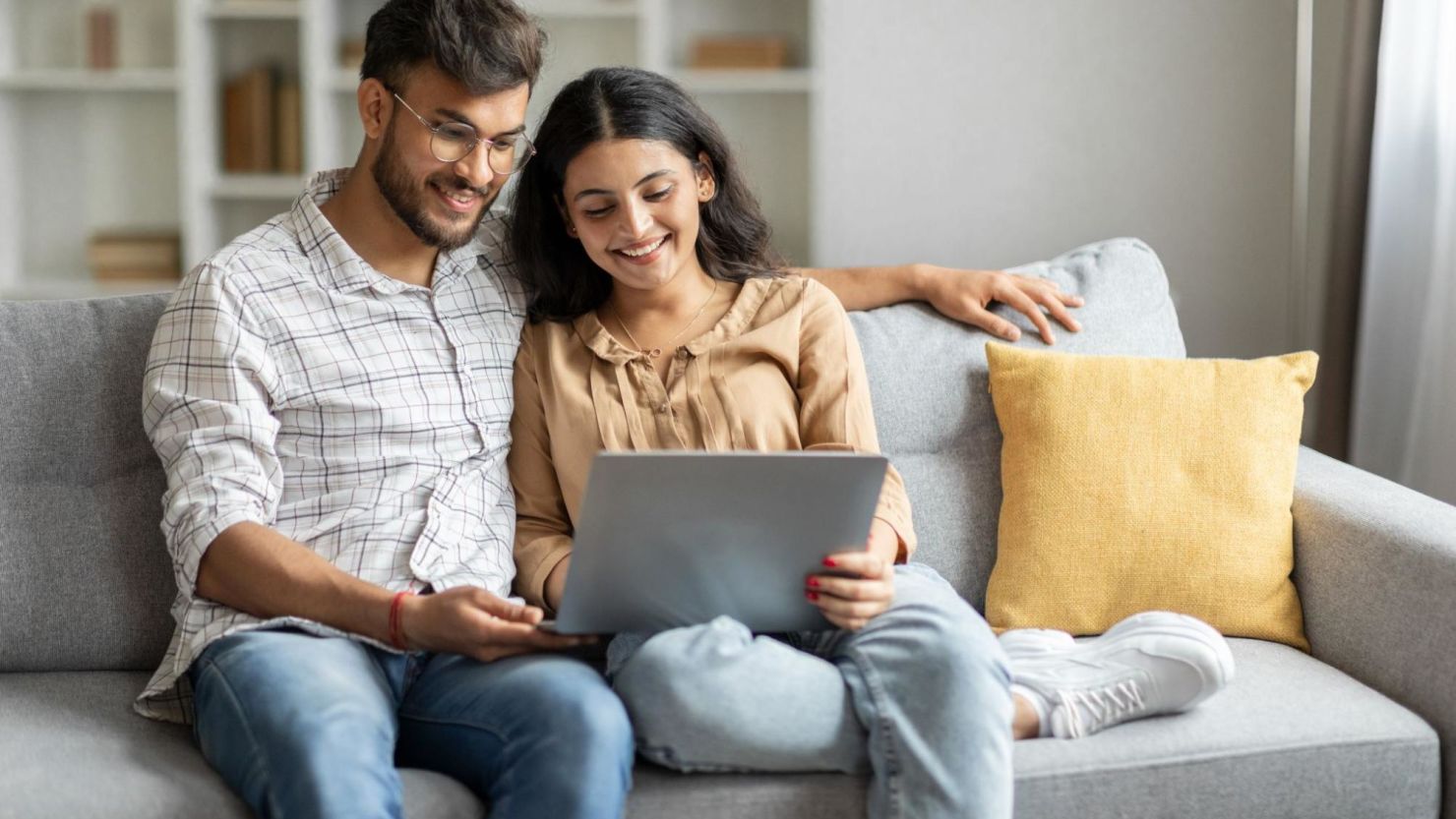 Couple sitting on the couch and looking at a computer screen.