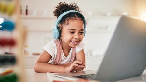 Kindergarten student on their laptop listening to a lesson.