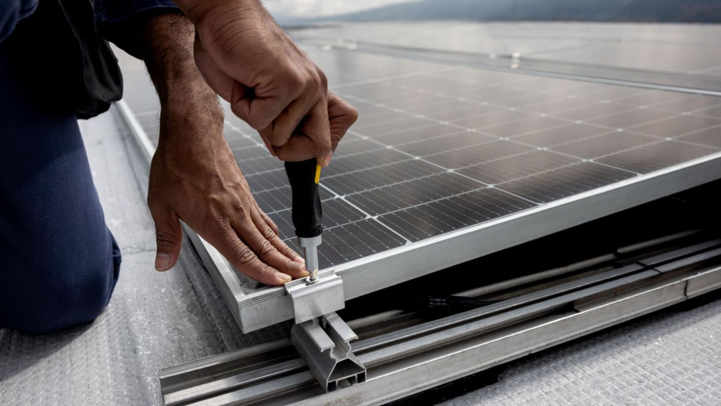 Solar installer screwing in a bolt on a solar panel.