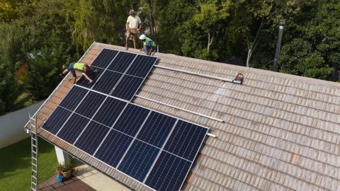 Three solar installers install a home solar system together.