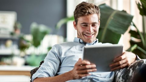 Internet user sitting on the couch while looking at a digital tablet.
