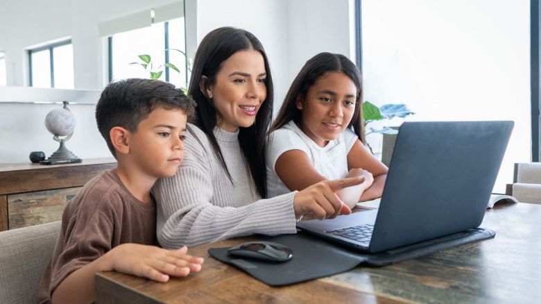 Family working on a laptop at the kitchen table.