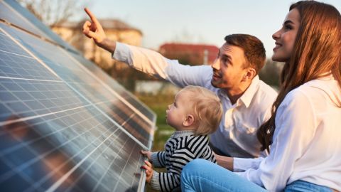 Man shows his family the ground-mounted solar panels.