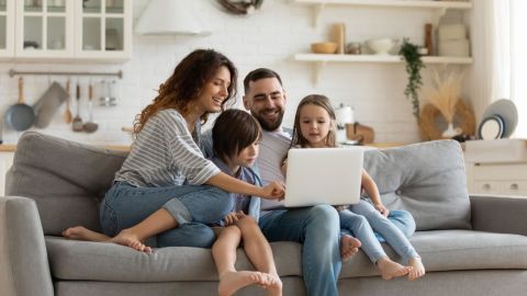 Family sitting on the couch while browsing the internet on a laptop.