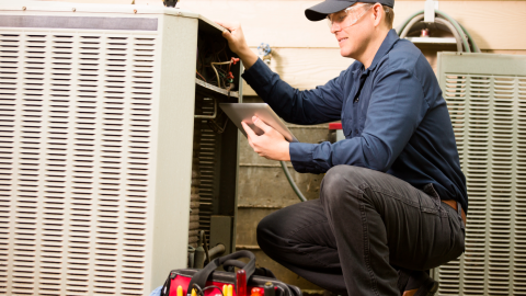 An HVAC technician fixes an air conditioner.