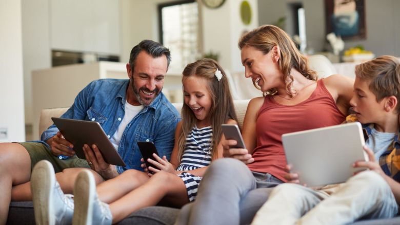 Family sitting on the couch while looking at their smart devices.