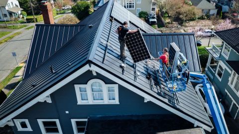 Solar technicians install solar panels on a roof.