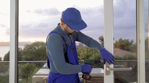 Window installer screwing a handle onto a patio door.