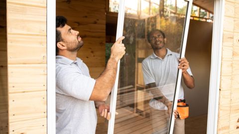 Two window installers putting a window into its frame