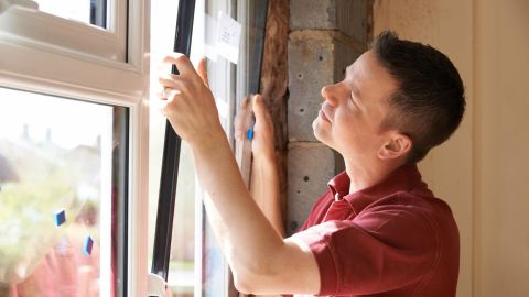 Window installer placing a window insert into its frame.