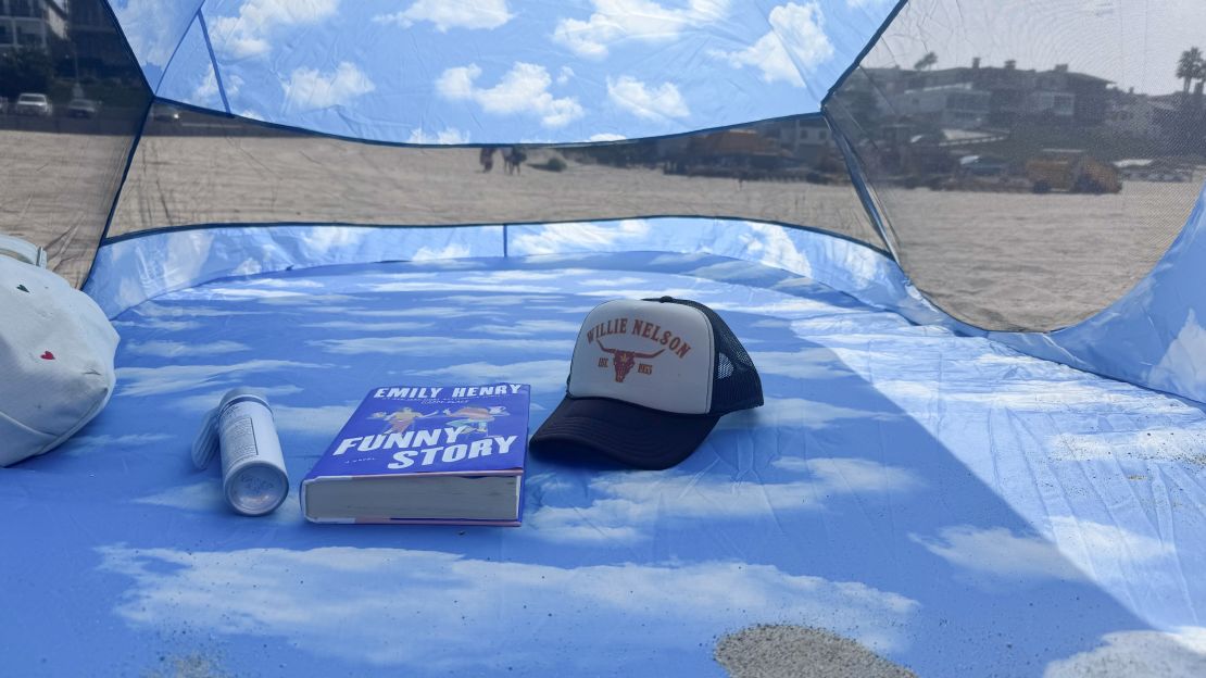 Inside of Pop Up tent with bag, sunscreen, book and hat placed in and around the center.