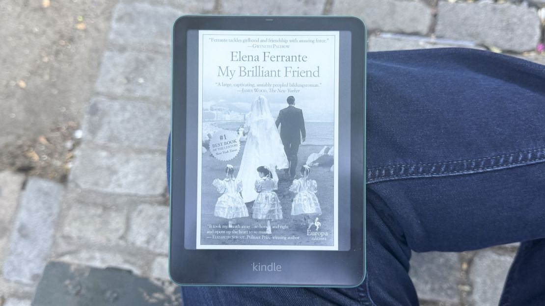 Amazon Kindle Paperwhite rests on knee with Elena Ferrante's My Brilliant Friend cover on its screen