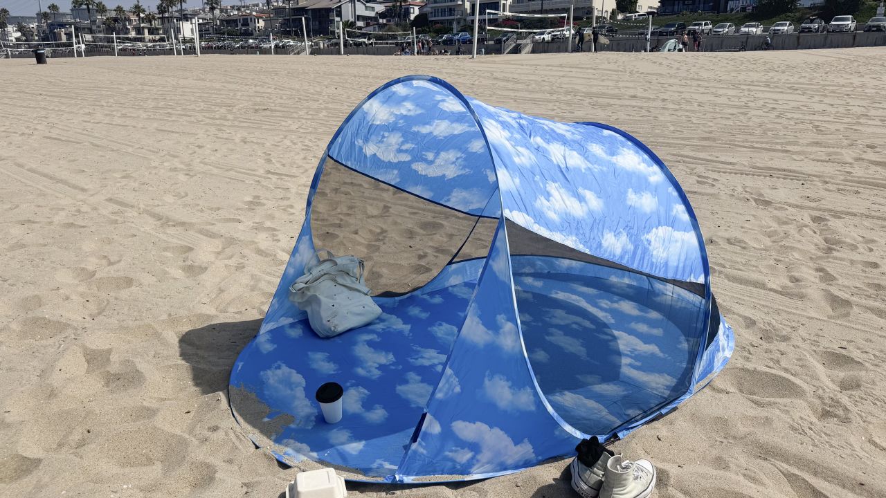 Baggu Pop Up Tent set up at the beach. Small bag inside and coffee and shoes placed outside.