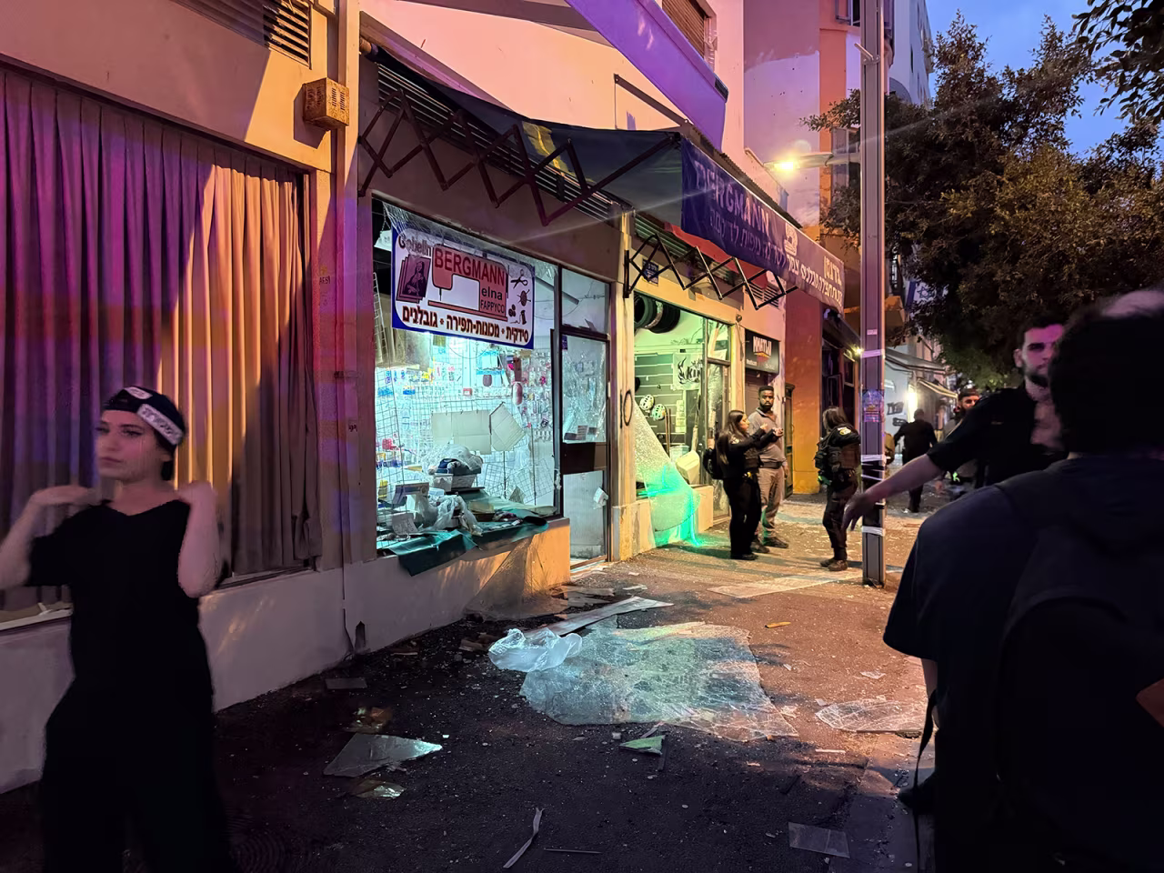People walk past a damaged shop following an Iranian missile strike on central Tel Aviv, Israel on Monday.