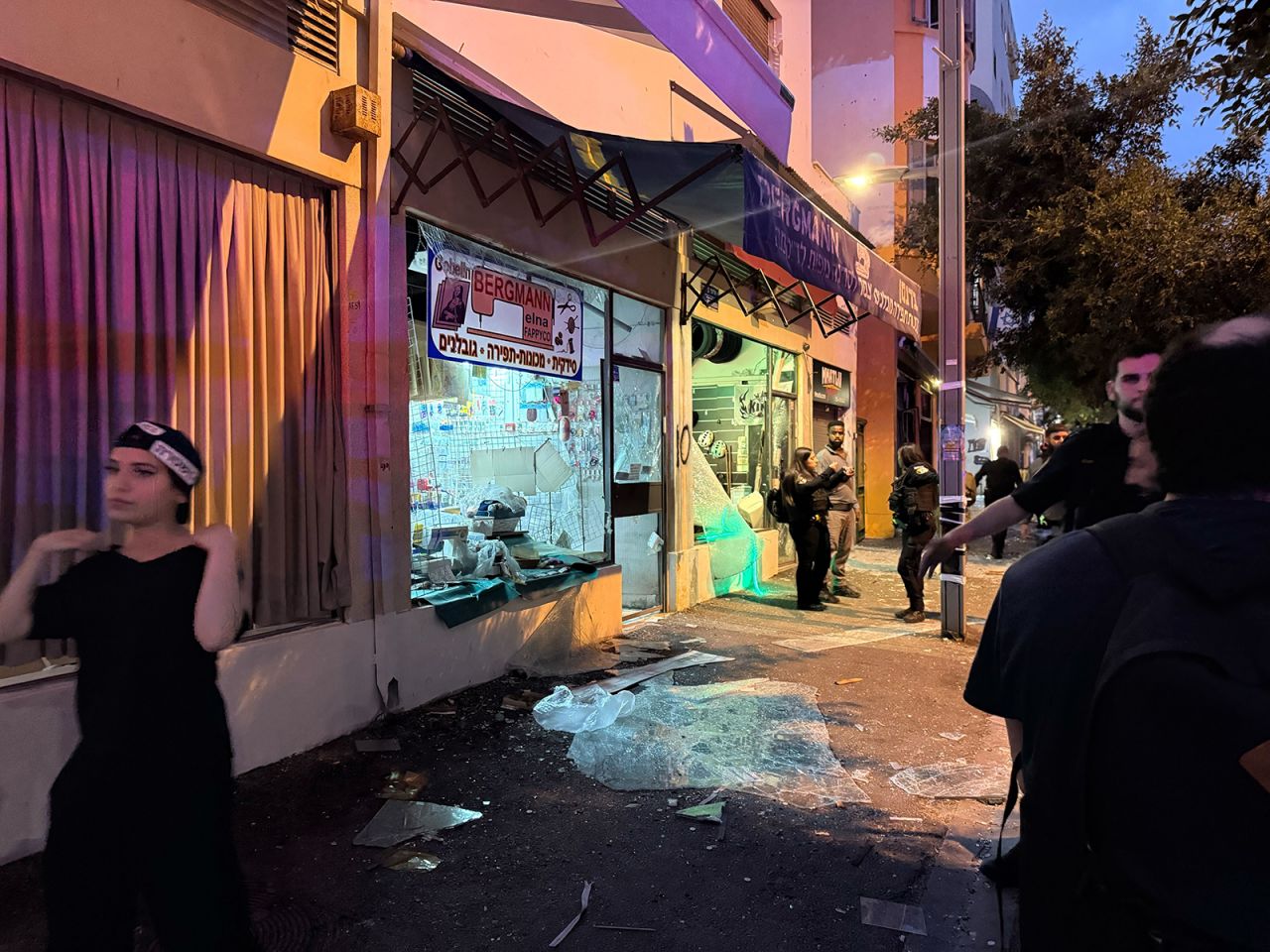 People walk past a damaged shop following an Iranian missile strike on central Tel Aviv, Israel on Monday.