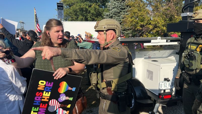 Protesters rally outside Illinois facility as Kristi Noem watches from rooftop...