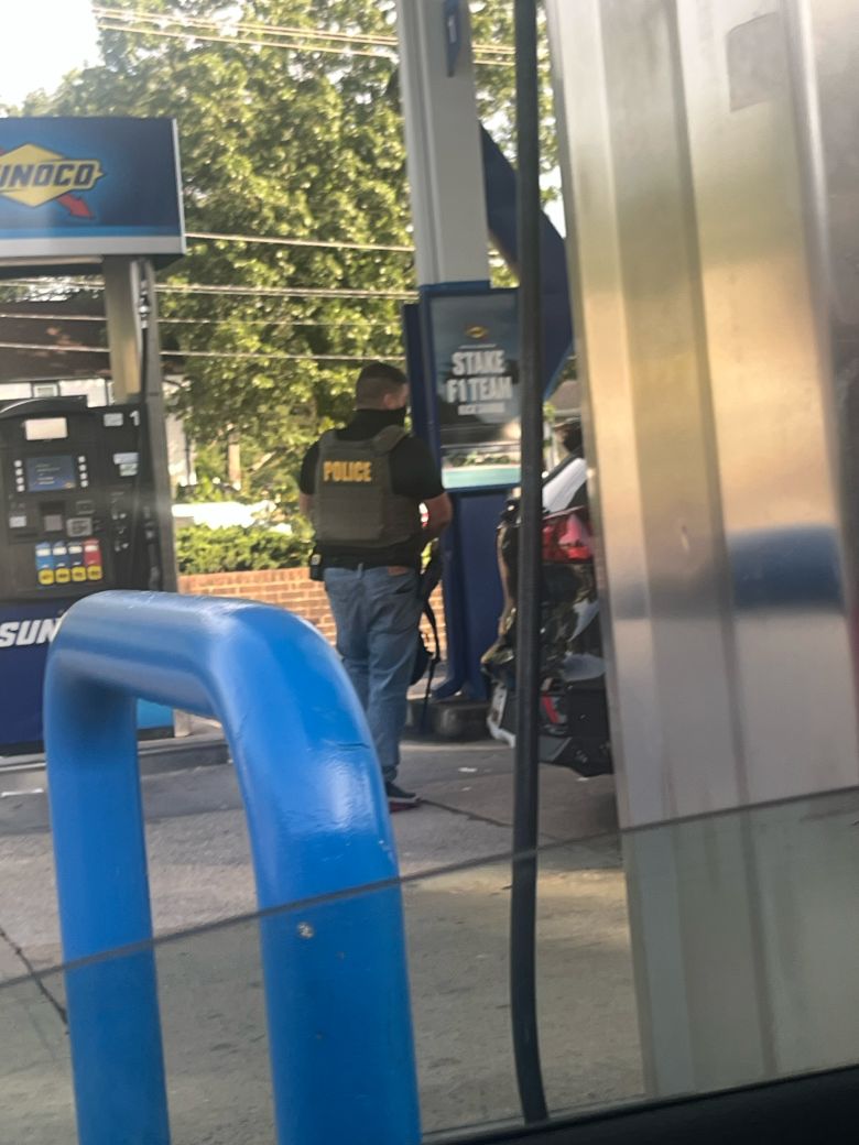 A masked ICE agent stands at a gas station in Takoma Park, Maryland.