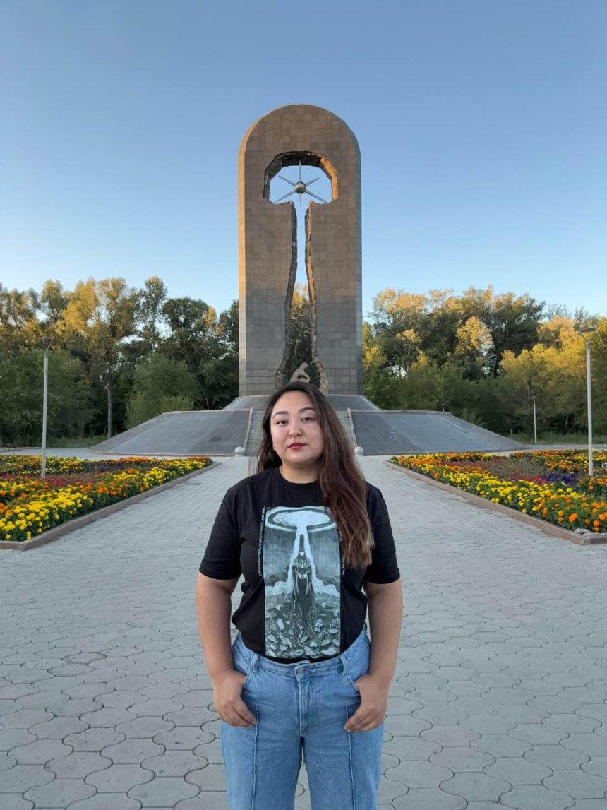 Aigerim Seitenova near a monument dedicated to nuclear survivors in her hometown of Semey. The monument depicts a mother shielding her child with her body from a mushroom cloud.