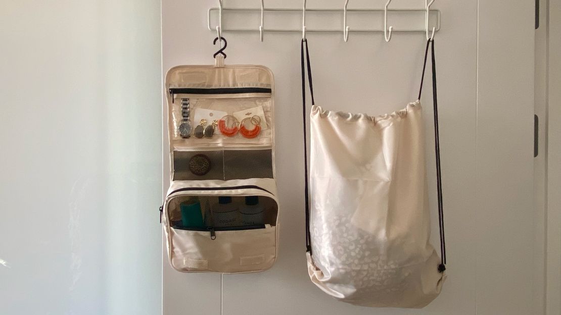 A photo of a Veken laundry bag and Veken toiletry bag hanging on a white door