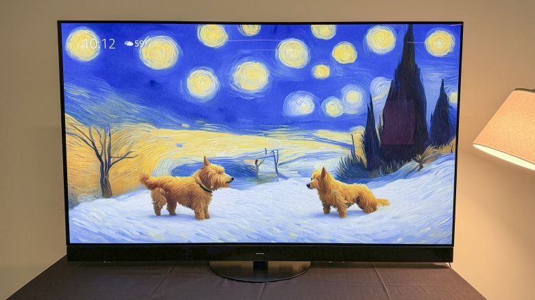 The Panasonic Z95A TV with a dogs in the style of Van Gogh image on the screen next to a lamp