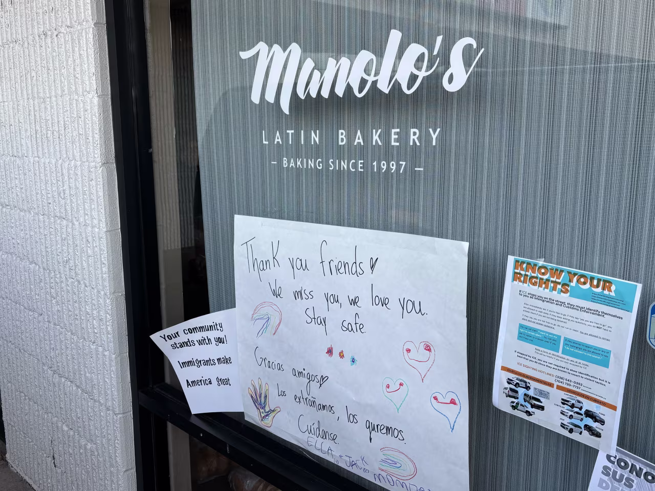 Signs on the front door of Manolo's Bakery are seen on Tuesday.