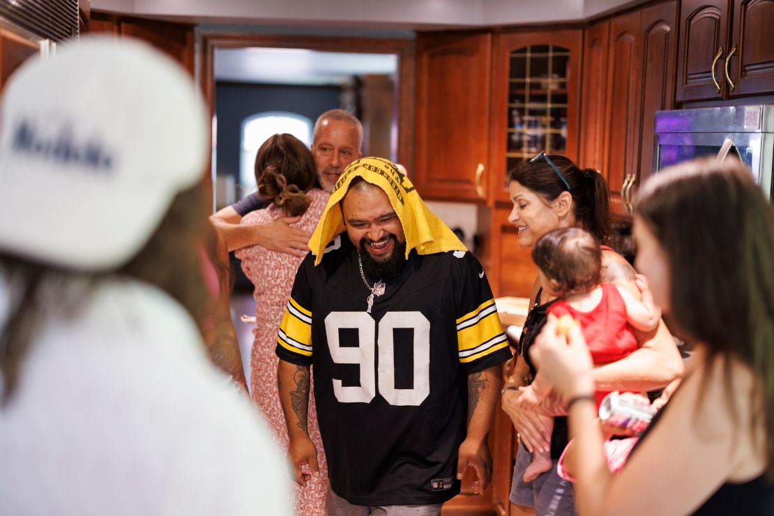 Julio walks through the kitchen wearing a Pittsburgh Steelers jersey and terrible towel.