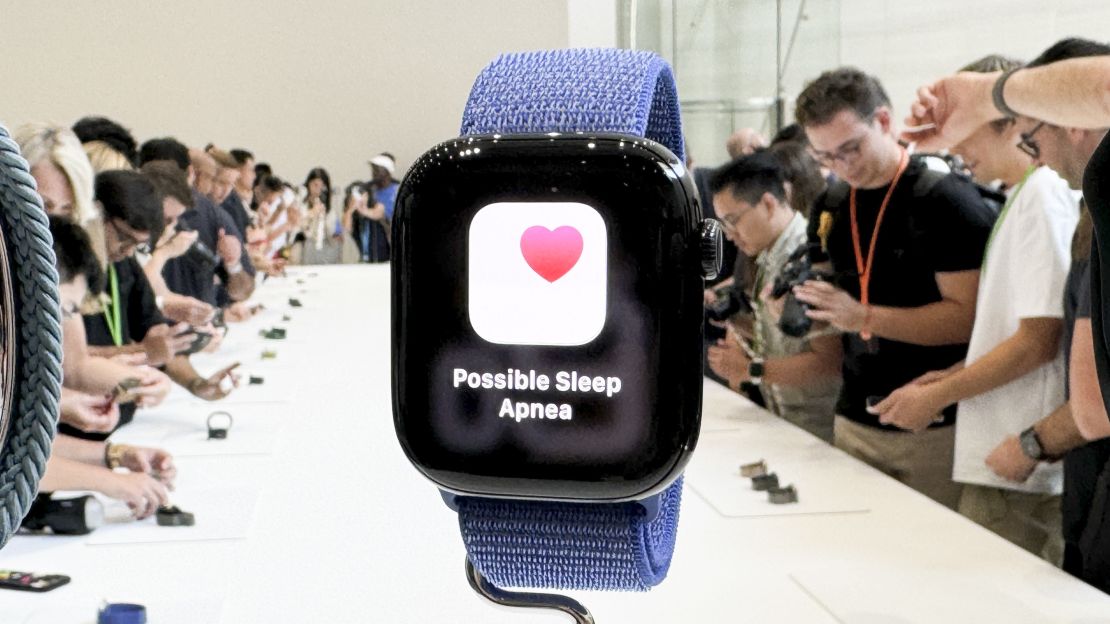 A "Possible Sleep Apnea" alert appears on the Apple Watch Series 10, with a crowded show floor in the background