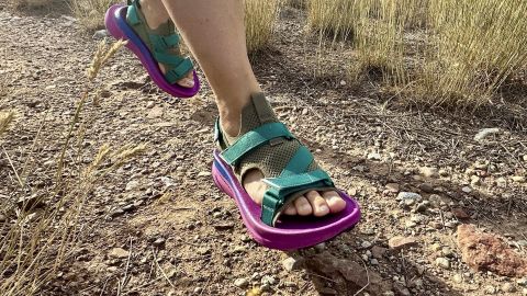 Feet of person running wearing Teva Aventrail sandals.